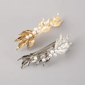 Close-up detail of golden and silver leaf hair clips with elegant pearl embellishments