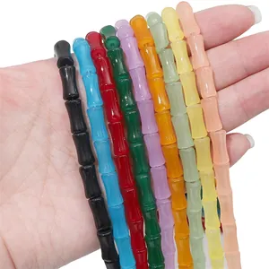 Colorful bamboo-shaped glass beads for DIY jewelry making, held in hand for scale.