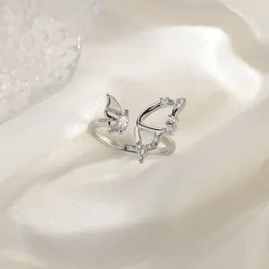 Detailed macro view of an asymmetric silver butterfly ring with zircon wings on silk.