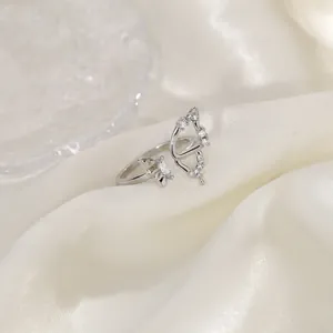 Close-up of asymmetric hollow butterfly ring with sparkling zircons on silk fabric