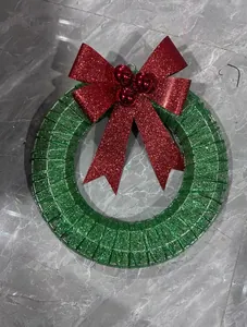Close-up view of a green metallic Christmas wreath with a large red glittery bow decoration