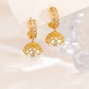 Detailed close-up view of golden heart filigree pearl drop earrings with soft bokeh