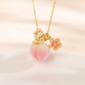 Close-up of pink peach pendant necklace with gold chain and shiny moissanite stones
