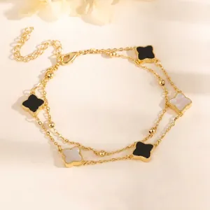 Close-up of gold double-layer bracelet featuring black and white clover charms