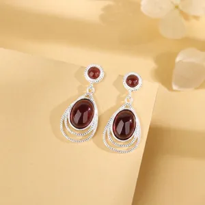 Close-up detail of elegant silver teardrop dangle earrings with deep red gemstones