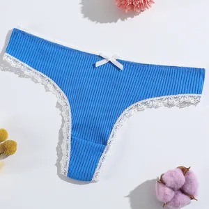 Bright blue ribbed cotton thong with white lace trim and bow on white background