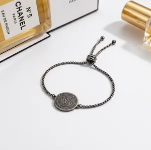 Close-up detail of adjustable silver stainless steel bracelet with engraved charm