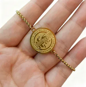 Detailed view of gold stainless steel St. Benedict medal bracelet held in hand