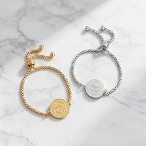 Detailed macro view of gold and silver adjustable box chain bracelets with saint medals