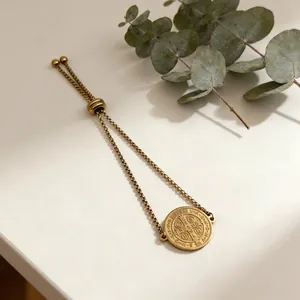 Close-up of a gold adjustable stainless steel bracelet with a religious coin pendant