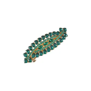 Macro detail view of emerald green crystal rhinestones on a gold leaf-shaped spring hair clip.