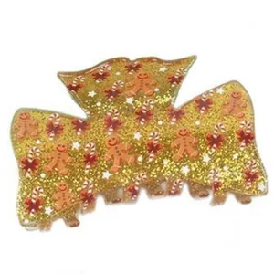 Close-up of golden glitter Christmas hair claw clip with gingerbread man motifs