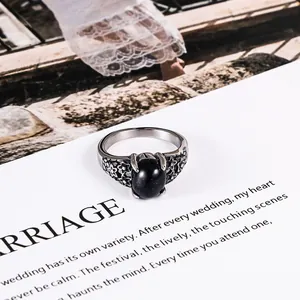Vintage floral stainless steel ring with black oval gemstone on an artistic paper