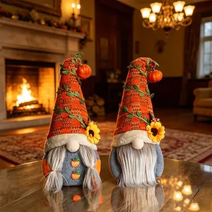 Deux gnomes de récolte en peluche avec citrouille et tournesol dans un cadre chaleureux.