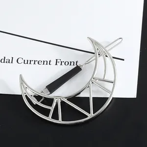 Close-up view of a silver-toned geometric moon-shaped hair clip with hollow patterns