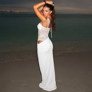 Elegant white lace patchwork maxi dress featuring side cut-out on a scenic sunset beach.