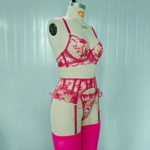 Dettaglio del ricamo floreale del set di lingerie rosa con reggicalze su manichino.