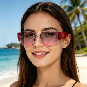 Stylish rimless sunglasses with gradient lenses and red temples in a beach setting.
