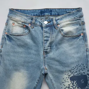 Vue détaillée d'un jean en denim bleu clair ajusté avec un motif d'éclaboussures d'encre