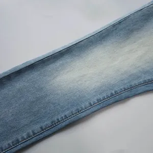 Gros plan sur un tissu denim bleu clair avec texture effet éclaboussure et finitions de couture
