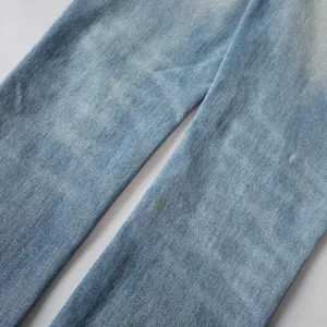 Vue détaillée d'un jean bleu clair délavé avec un subtil effet de taches de peinture