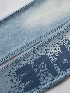 Détail d'un jean bleu clair avec imprimé lettres à effet éclaboussure de peinture bleu