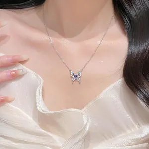 Close-up of a silver butterfly necklace with a purple heart stone worn by a model