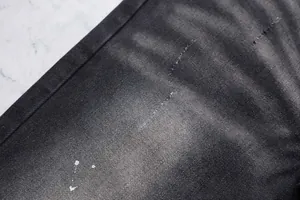 Gros plan de jean noir évasé montrant le denim délavé et les éclaboussures de peinture