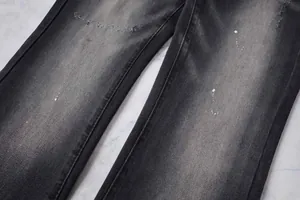 Gros plan d'un jean évasé noir délavé avec des taches de peinture et une texture denim.