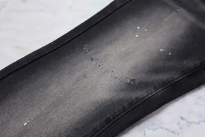 Gros plan sur un jean évasé noir vieilli avec des taches de peinture blanche