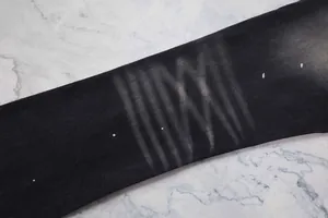 Gros plan sur un denim noir montrant des effets de délavage moustaches et des éclats
