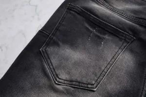 Détail du tissu denim délavé noir sur la poche arrière du jean évasé pour homme chic.