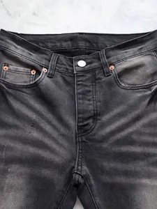 Gros plan d'un jean évasé noir délavé pour homme avec texture denim vintage et rivets