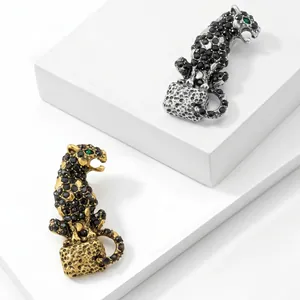 Detailed view of luxury leopard brooch with black rhinestones and green gem eyes.