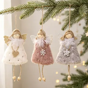 Close-up of three plush angel girl ornaments hanging on a Christmas tree branch.