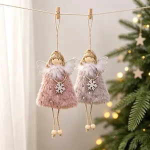 Two plush Christmas angel doll ornaments hanging by twine with a festive holiday tree background