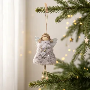 Detail of a grey plush Christmas angel girl ornament hanging on a pine tree branch
