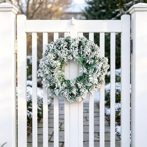 Beautiful snowy pine Christmas wreath decoration hanging on a white wooden garden gate