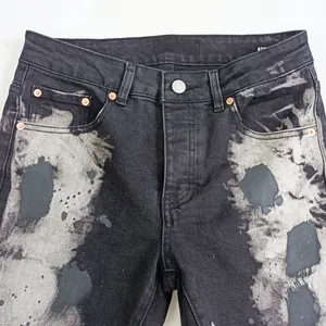 Vista dettagliata di jeans grigio neri con motivo a schizzi e rivetti in rame