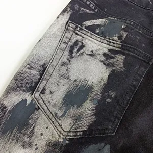 Dettaglio della tasca posteriore di jeans denim uomo nero e grigio con schizzi.