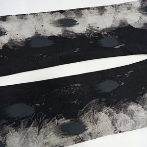 Dettaglio ravvicinato della trama astratta a macchie d'inchiostro nero e grigio su tessuto denim.