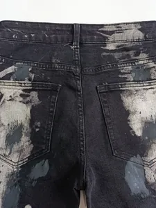Primo piano delle tasche posteriori di jeans svasati grigio nero con lavaggio vernice