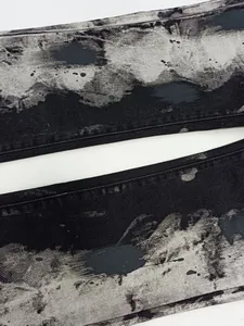 Vista ravvicinata dettagliata del tessuto denim lavato nero e grigio effetto inchiostro.