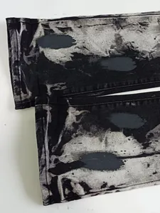 Vista dettagliata di jeans in denim lavato nero grigio con stampa splatter unica per uomini