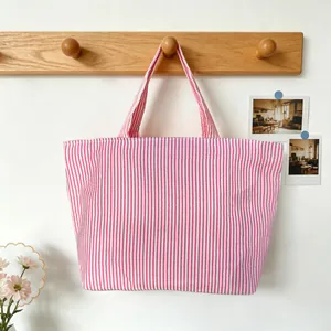Detailed view of pink and white vertical striped canvas tote bag hanging on wooden rack