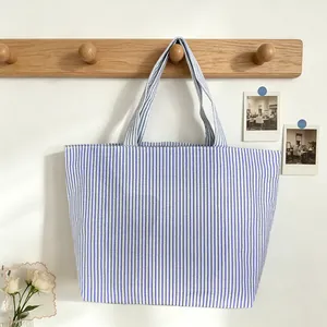 Detailed view of a blue and white striped tote bag hanging on a wooden wall rack