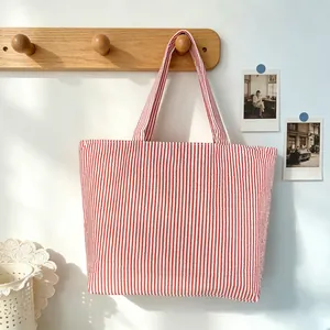Large red and white striped tote bag hanging on a wooden hook in a bright lifestyle setting