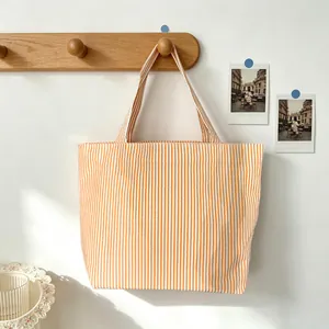 Close-up of an orange and white striped canvas tote bag hanging on a wooden hook