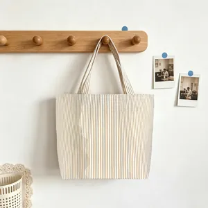 Striped canvas tote bag hanging on a wooden wall hook for a stylish storage display.