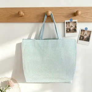 Detailed view of a light blue and white striped tote bag hanging on a wooden rack